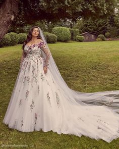 a woman in a wedding dress standing under a tree