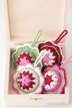 four crocheted ornaments in a white box with pink and green trimmings