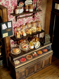 an assortment of pastries are on display in a room with pink wallpaper and wood flooring