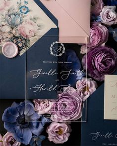 the wedding stationery is laid out on top of each other, with different colored paper flowers