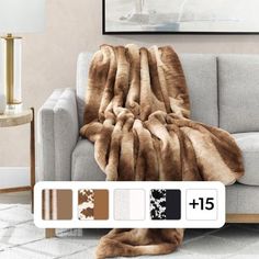 a couch with a blanket on top of it next to a lamp and pictures in the background