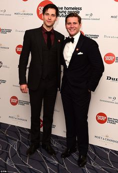 two men standing next to each other in front of a red and white carpeted wall