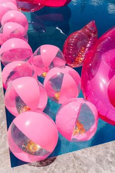 many pink balloons floating in the water next to each other on top of a blue surface