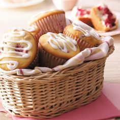 a basket filled with muffins sitting on top of a pink place mat next to cupcakes