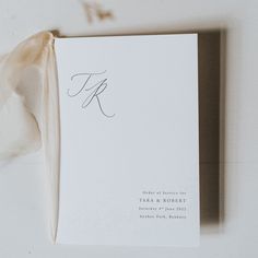 a white wedding program with a ribbon tied around the front and back of it's envelope