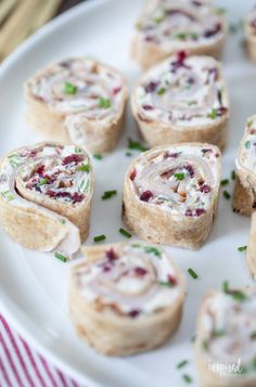 several small rolls on a white plate with green garnish