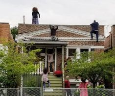 three people standing on the roof of a house with their hands up in the air