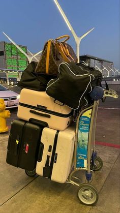 several pieces of luggage are stacked on top of each other in a cart near a yellow fire hydrant