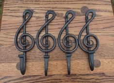 three metal music notes are sitting on a wooden board with black handles and hooks attached to them