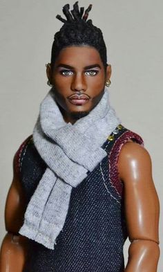 a close up of a doll wearing a sweater and scarf with dreadlocks on his head