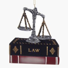 a law book ornament hanging from a chain on a white background in the shape of a scale