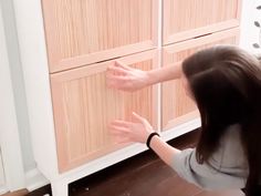 a woman reaching for something on the side of a cabinet with her hands in it