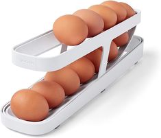 an egg roller with six brown eggs in it on a white background and attached to the side