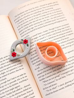 an open book with two rings on top of it and a flower brooch in the middle