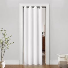 a white curtain hanging on the side of a door next to a potted plant