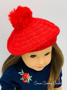 a doll wearing a red knitted hat with a pom - pom on top