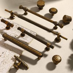 an assortment of brass knobs and handles on a white surface with holes in the middle