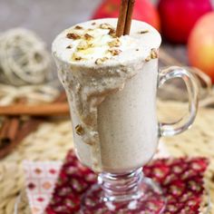 there is a drink with whipped cream and cinnamon in it on the table next to apples