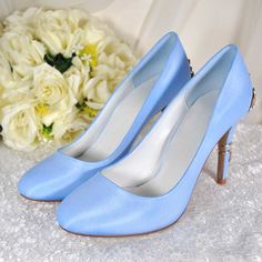 a pair of blue high heels sitting on top of a table next to white flowers