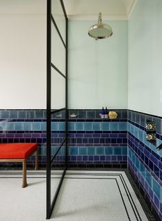 a blue tiled bathroom with a bench and shower head in the corner next to it