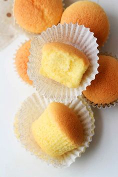 three cupcakes sitting on top of each other in white paper cups with yellow frosting