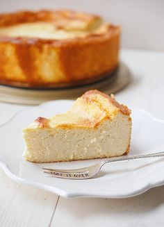 a piece of cheesecake on a white plate with a fork next to the pie