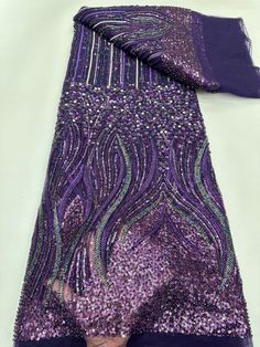 purple sequined dress with matching scarf on white tablecloth, close up view