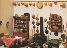 an old fashioned kitchen with many pots and pans hanging on the wall