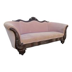 a pink couch sitting on top of a white floor next to a wooden frame with ornate carvings