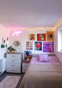 a bed room with a neatly made bed and posters on the wall