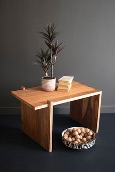 a wooden table with a bowl of nuts and a potted plant next to it