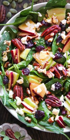 a salad with spinach, apples, cranberries and pecans