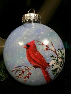 a glass ornament with a red cardinal painted on it