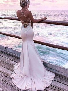 a woman standing on a pier looking out at the ocean with her back to the camera