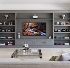 a living room filled with furniture and a flat screen tv mounted on a wall above a fireplace