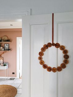 a door with a wreath hanging on it's side in front of a pink wall