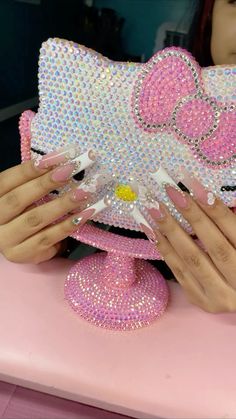 a woman with pink nails holding up a hello kitty purse