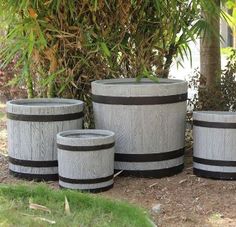 three wooden barrels sitting next to each other in front of a tree and grass area