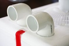 two white cups sitting on top of a foamy surface next to a red tube