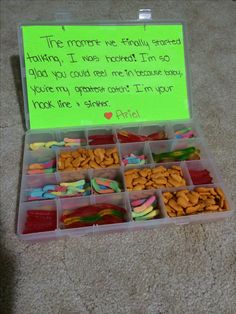 a plastic container filled with lots of food on top of a floor next to a green sign