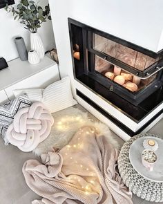 an open oven with candles and blankets on the floor next to it in a living room