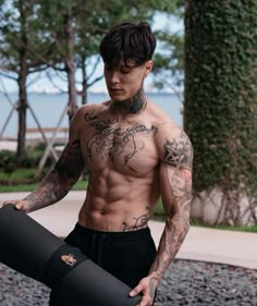 a man with tattoos holding a yoga mat