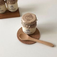 two jars of peanut butter sitting on top of coasters next to a wooden spoon