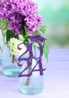 two vases filled with purple and white flowers on top of a wooden table next to each other