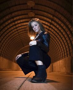 a woman is posing in a tunnel with her legs crossed and boots on the ground