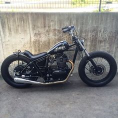 a black motorcycle parked next to a concrete wall