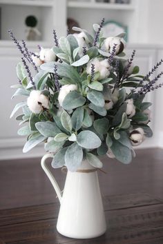 a white vase filled with flowers on top of a wooden table