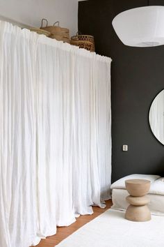 a white bed sitting next to a mirror on top of a wall