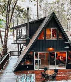 a - frame cabin in the woods surrounded by trees and decking is perfect for an outdoor dining area