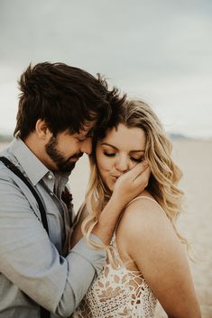 a man and woman embracing each other on the beach